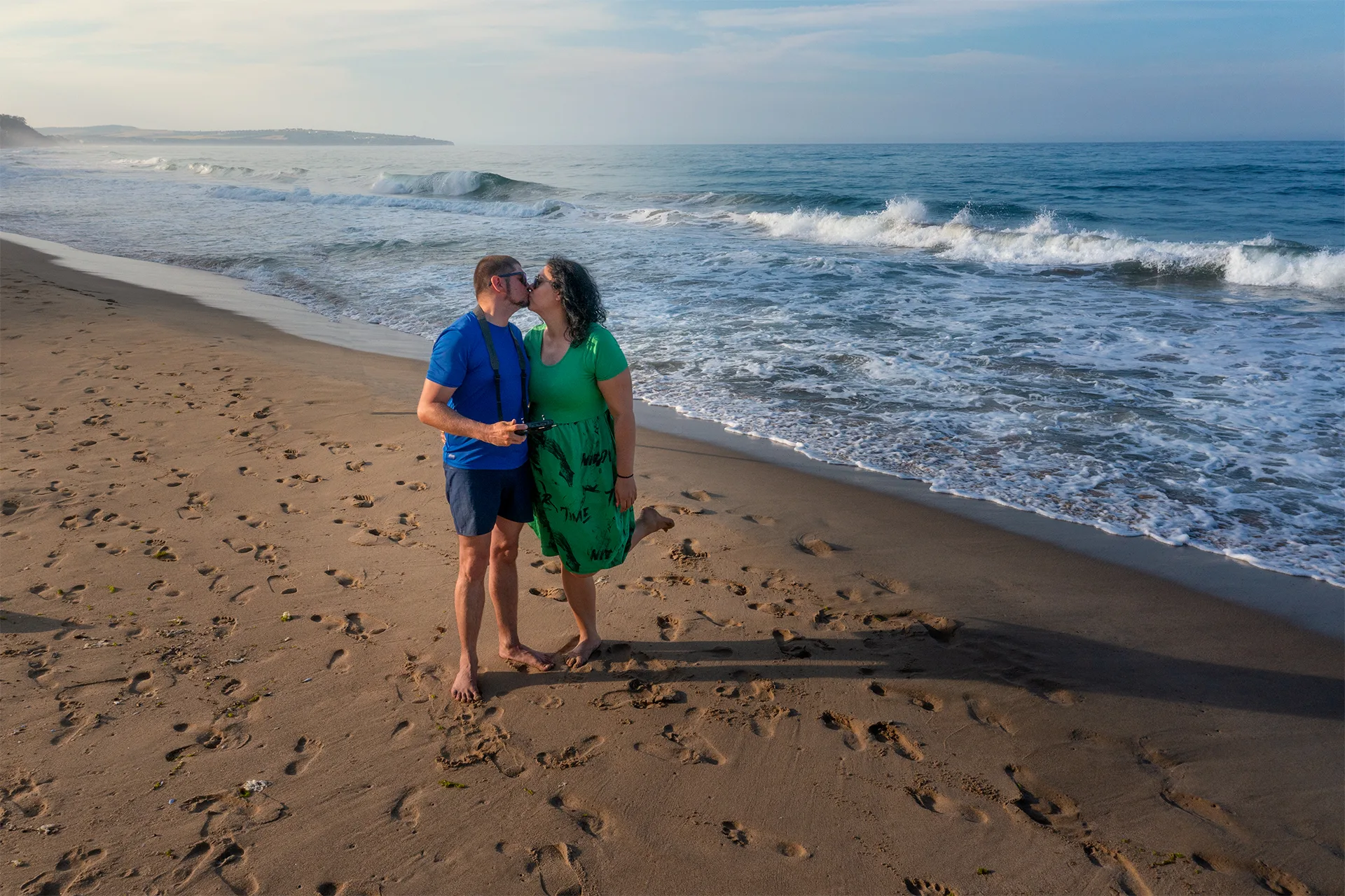 A couple standing together on a sandy beach beside the waves during their summer journey along the Black Sea coast.