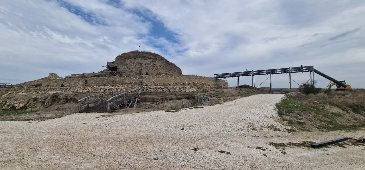 Wide view of the archaeological site at Provadia-Solnitsata, with excavated stone walls, wooden walkways and ongoing work around the prehistoric settlement.