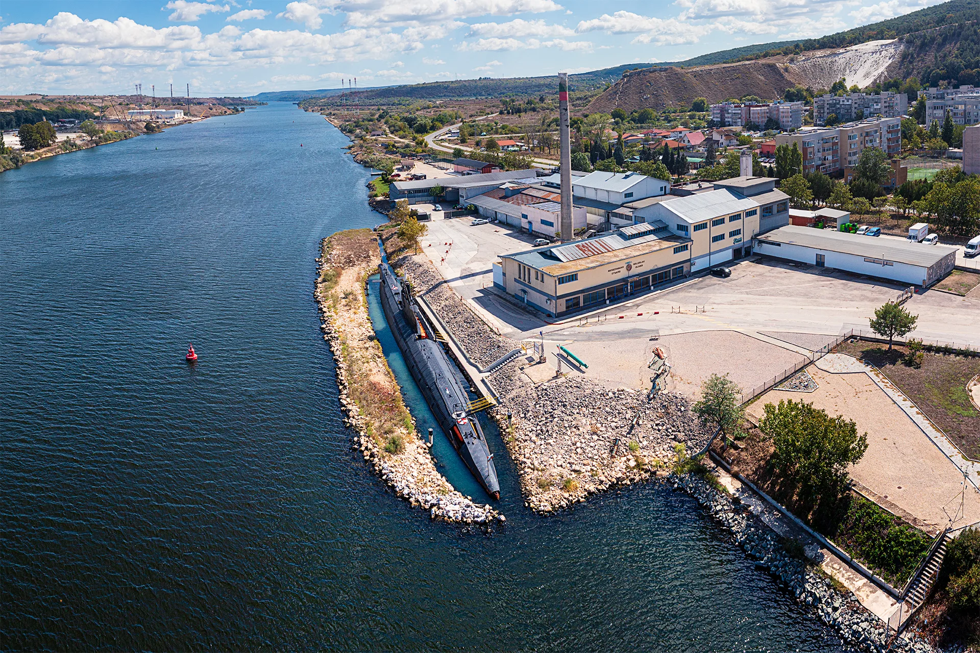 Aerial view of the Slava submarine moored beside the Museum of Glass in Beloslav, with the canal and the town in the background.