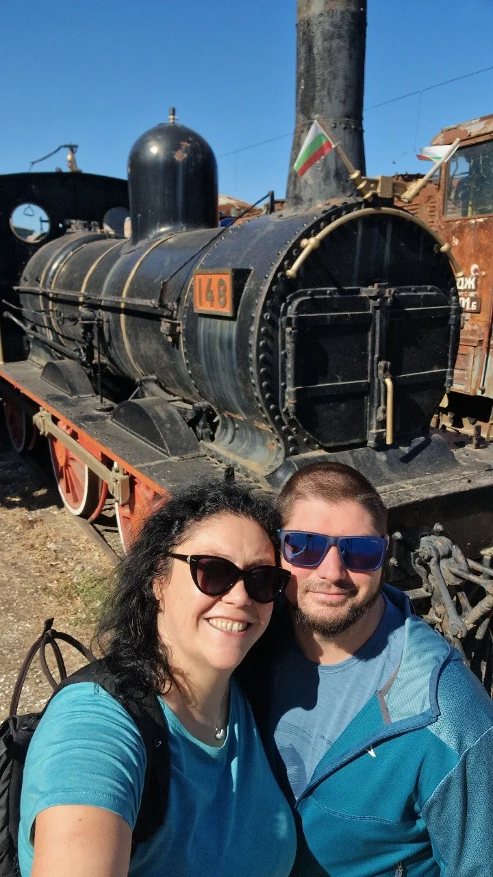 Two visitors posing in front of historic steam locomotive No. 148 at the Museum of Transport in Ruse.