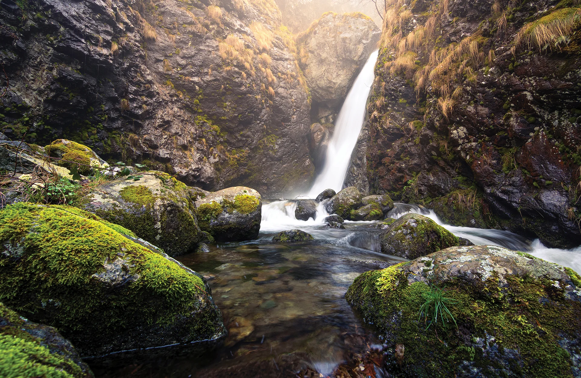 Goritsa Waterfall flowing between dark cliffs and moss-covered rocks near Ovchartsi