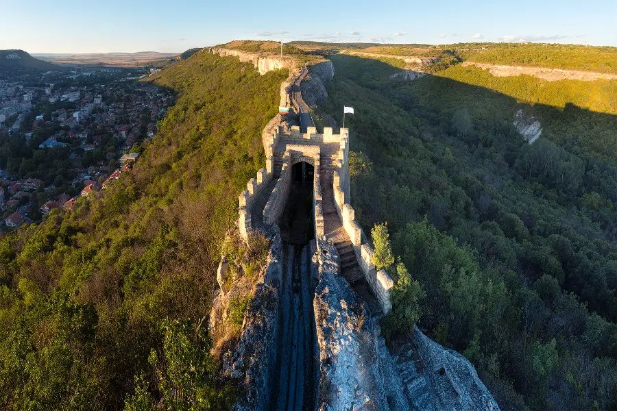 Aerial view of Ovech Fortress stretching along a narrow rocky ridge above Provadia, surrounded by forested slopes.