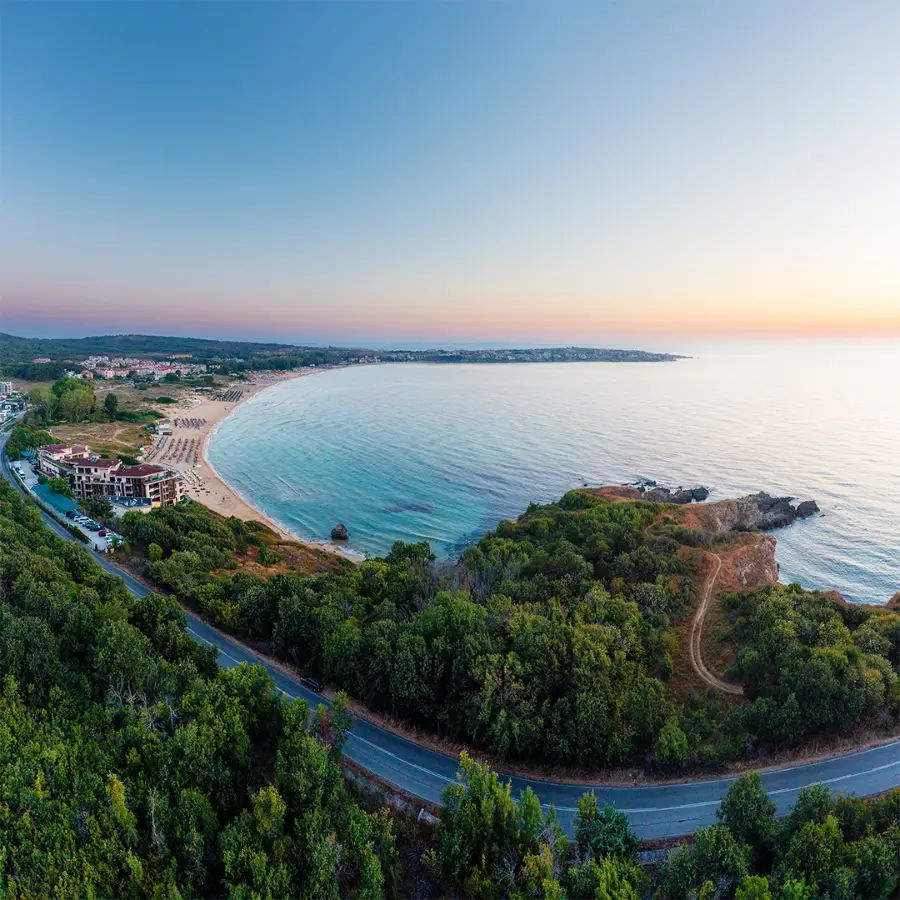 Aerial view of Smokinya and Kavatsi Bay near Sozopol before sunrise, with pastel sky, calm water and the beach curving around the bay.