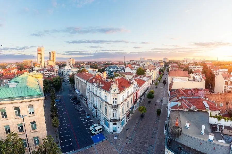Aerial view over central Ruse in the early morning, with historic buildings, red rooftops and a pedestrian street leading through the city.
